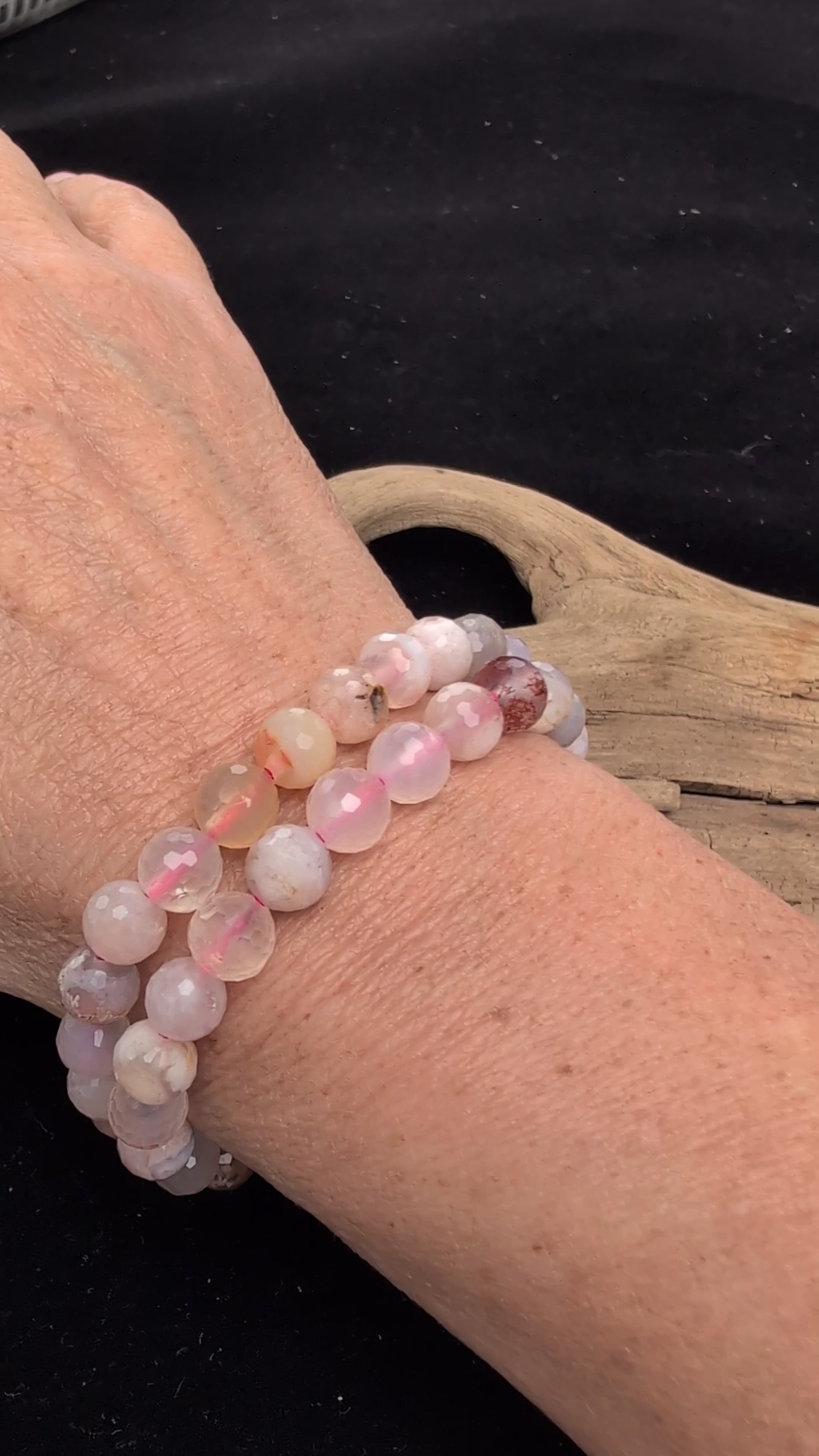 Video demonstrating the 8mm faceted Flower Agate beaded stretch bracelet in motion, highlighting the light-catching geometric cuts and the natural three-dimensional chalcedony blossom formations within the matrix, strung on a pink elastic cord.