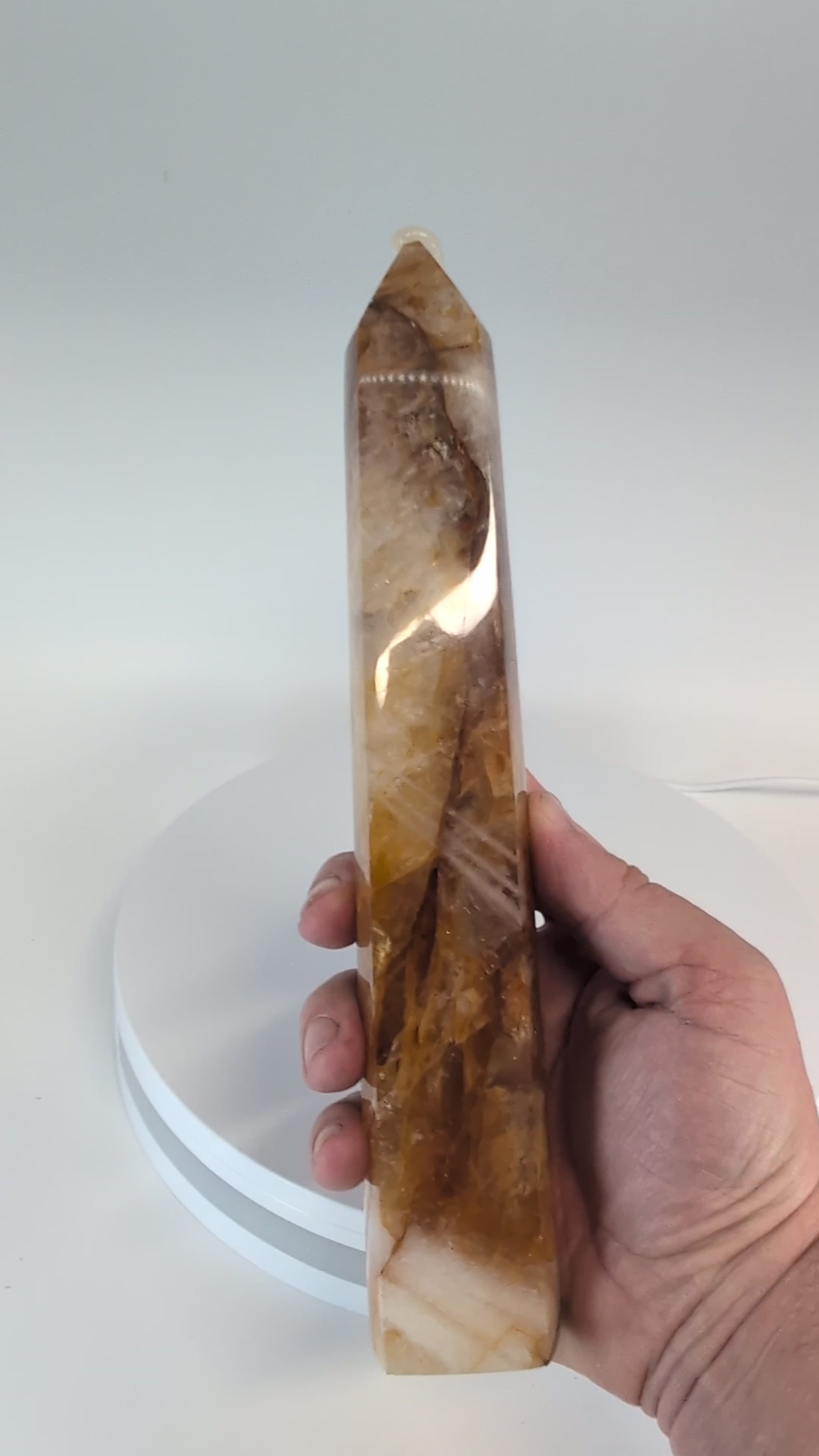 Brazilian Golden Healer Quartz Tower illuminated from behind — internal golden bands and translucent structure glowing through quartz under light.