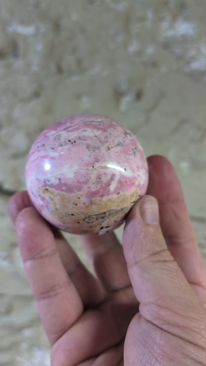 video of Polished rhodonite sphere close-up with black manganese inclusions