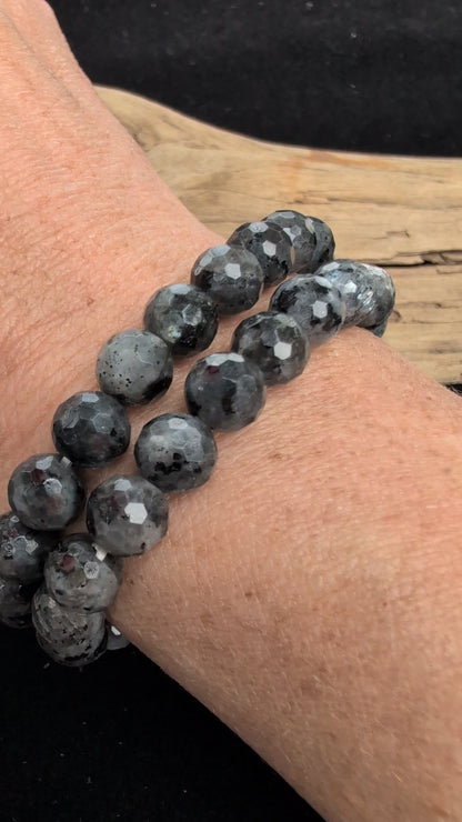 Video showcasing the highly reflective faceted texture, dark grey matrix, and brilliant silver-blue optical flash (schiller effect) of an 8mm Larvikite beaded stretch bracelet worn on a wrist.