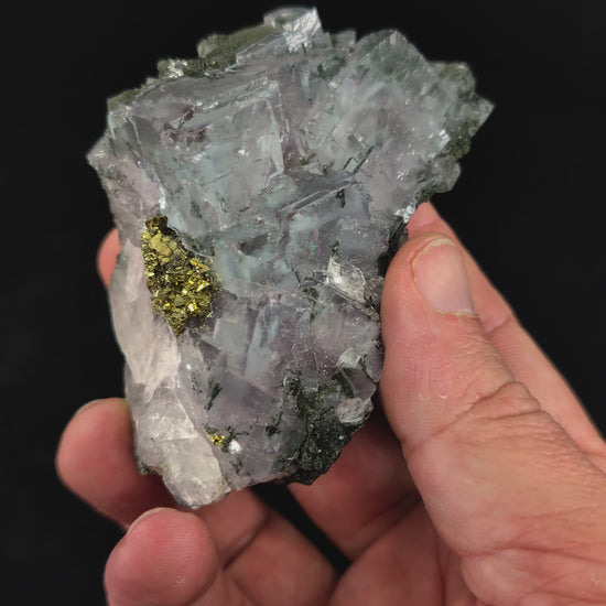 360-degree video of YGX fluorite with pyrite, showing crystal clarity, rainbow zoning, matrix base, and UV-reactive surfaces under shifting light