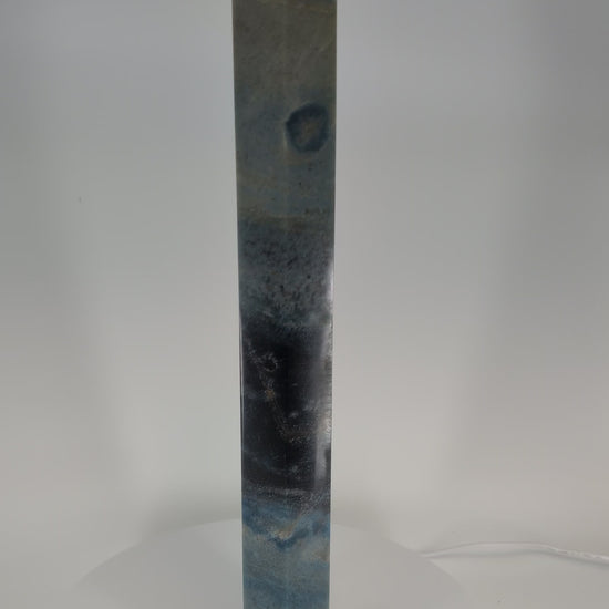 360-degree video of Trollite Tower TR-01 — a 17-inch (43 cm) polished blue-green crystal tower from Minas Gerais, Brazil, showing its gradient color zoning, reflective finish, and mica shimmer in natural light.