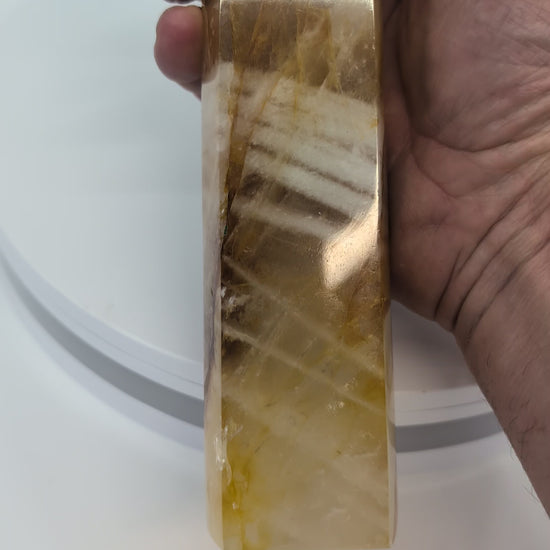 Tall Brazilian Golden Healer Quartz Tower illuminated from behind to reveal translucent golden bands and smoky quartz inclusions.