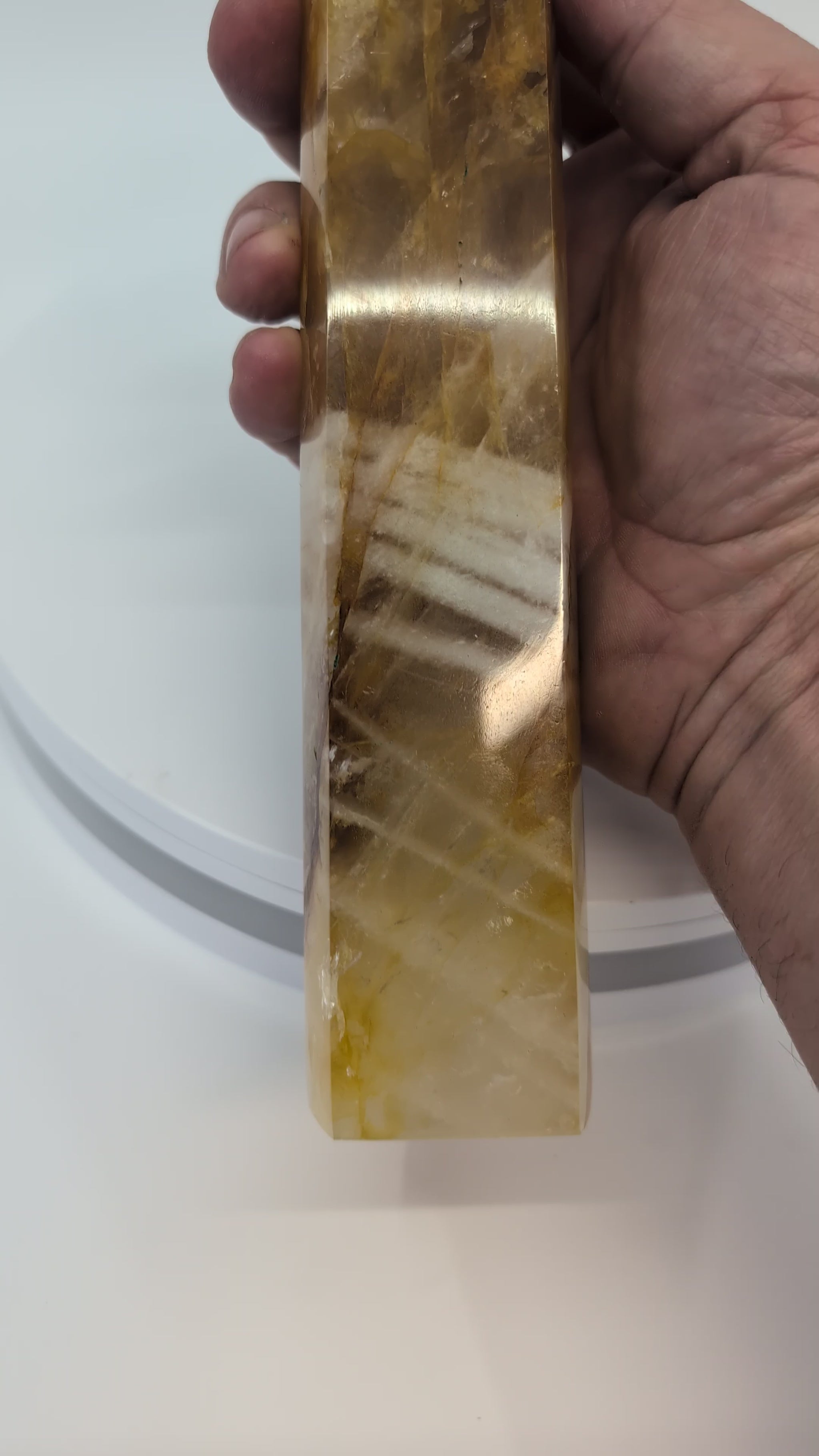 Tall Brazilian Golden Healer Quartz Tower illuminated from behind to reveal translucent golden bands and smoky quartz inclusions.
