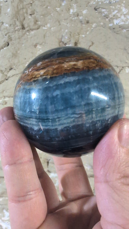Video of Polished banded calcite sphere with rich blue and sienna tones