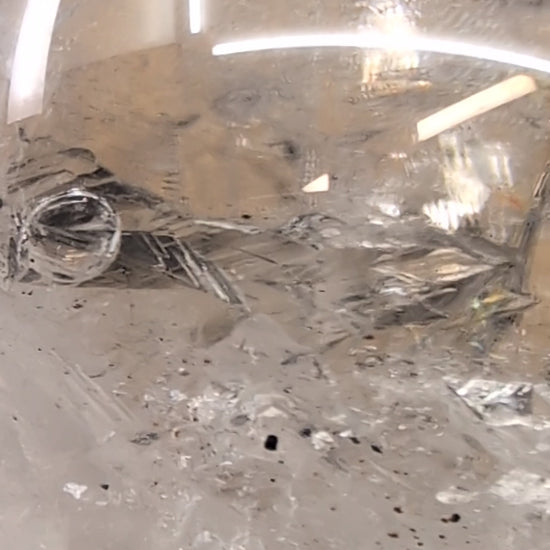 Close-up macro video capturing the dynamic movement of the ancient water bubble within the enhydro cavity of a 1.12 kg Brazilian clear quartz sphere.