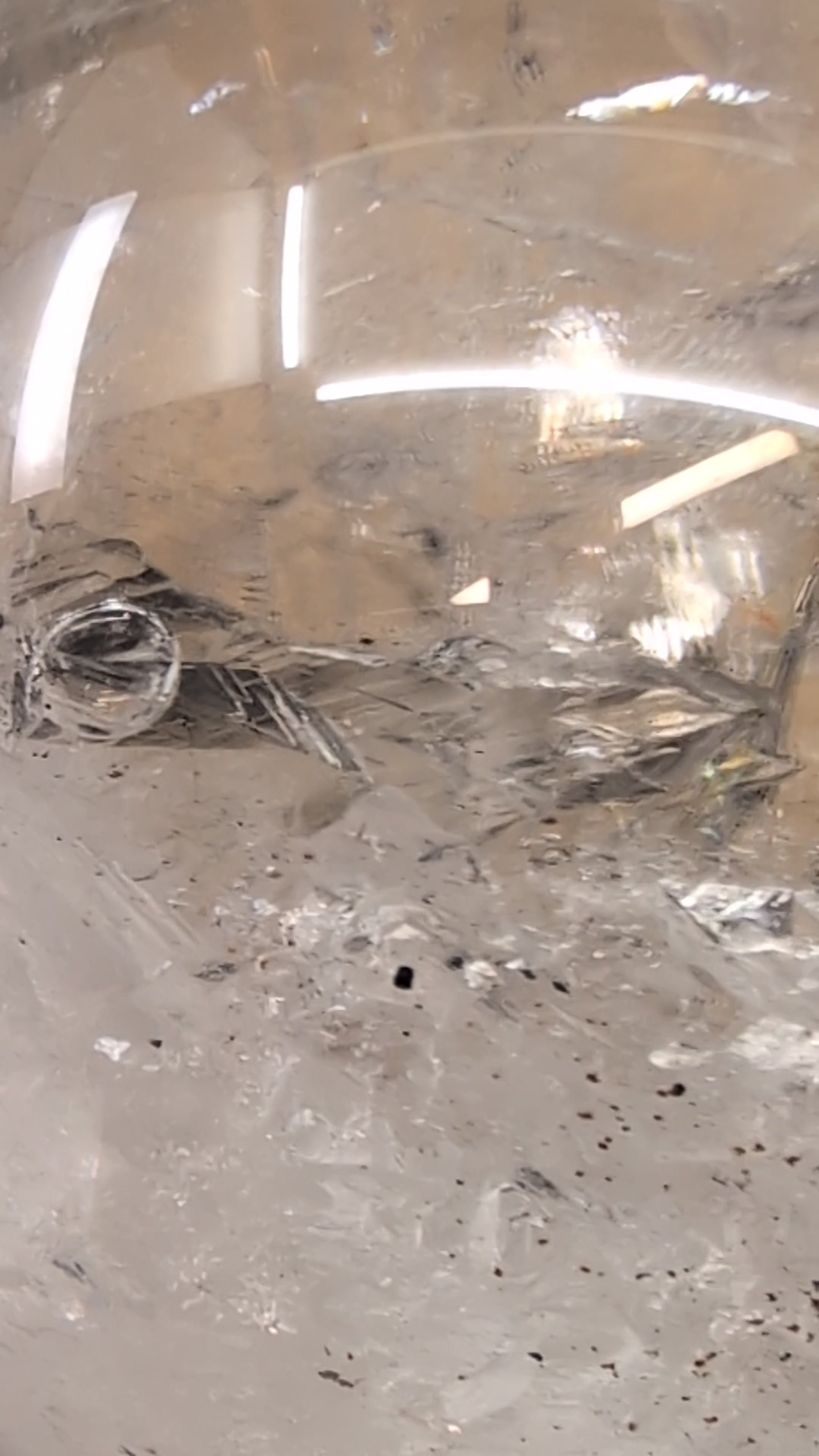 Close-up macro video capturing the dynamic movement of the ancient water bubble within the enhydro cavity of a 1.12 kg Brazilian clear quartz sphere.