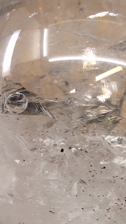 Close-up macro video capturing the dynamic movement of the ancient water bubble within the enhydro cavity of a 1.12 kg Brazilian clear quartz sphere.