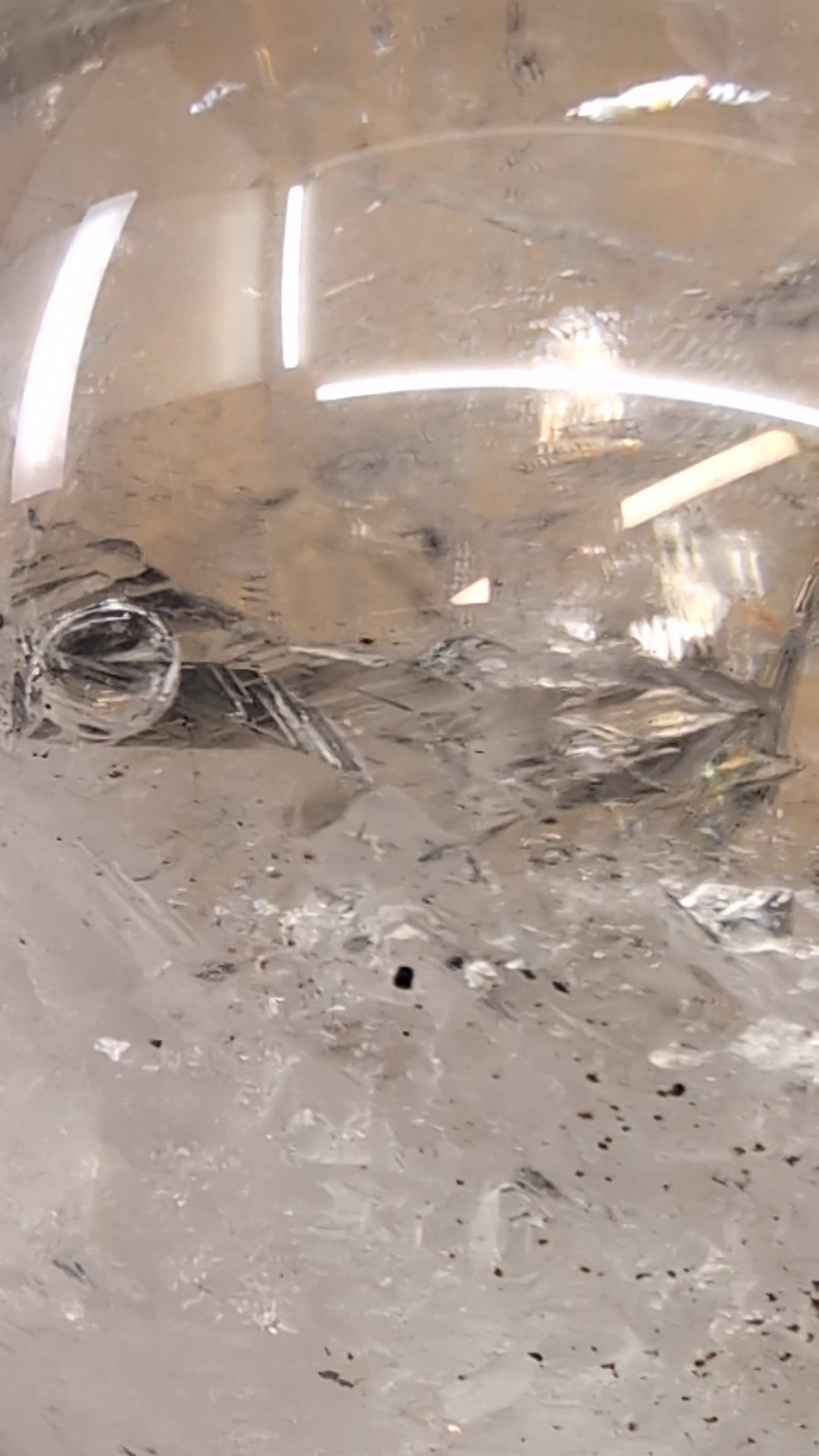 Close-up macro video capturing the dynamic movement of the ancient water bubble within the enhydro cavity of a 1.12 kg Brazilian clear quartz sphere.
