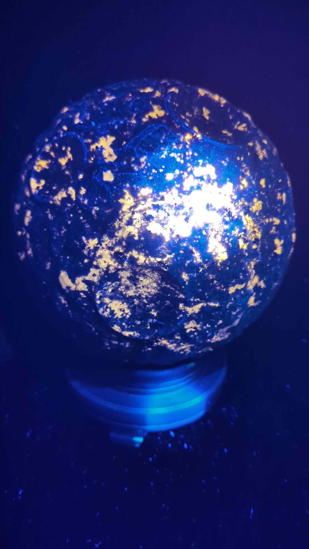A massive 210 mm (8.27 in) Yooperlite carved moon sphere glowing intensely orange under UV light, highlighting natural sodalite inclusions.