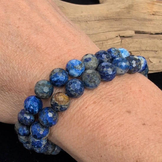 Video showcasing the highly reflective faceted texture, deep blue matrix, and flashing golden pyrite inclusions of an 8mm Lapis Lazuli beaded stretch bracelet worn on a wrist.
