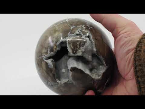 Video showing the 360-degree rotation of a Volcano Agate sphere transitioning from natural light to a neon green UV-reactive glow.