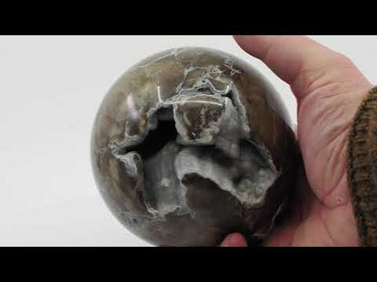 Video showing the 360-degree rotation of a Volcano Agate sphere transitioning from natural light to a neon green UV-reactive glow.