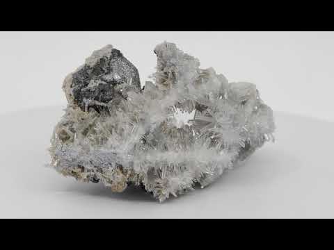 360-degree rotating view of a rare Burmese mineral specimen. The video displays sharp, striated black pyrite crystals and a heavy massive galena base suspended in a fragile nest of clear jackstraw quartz needles.