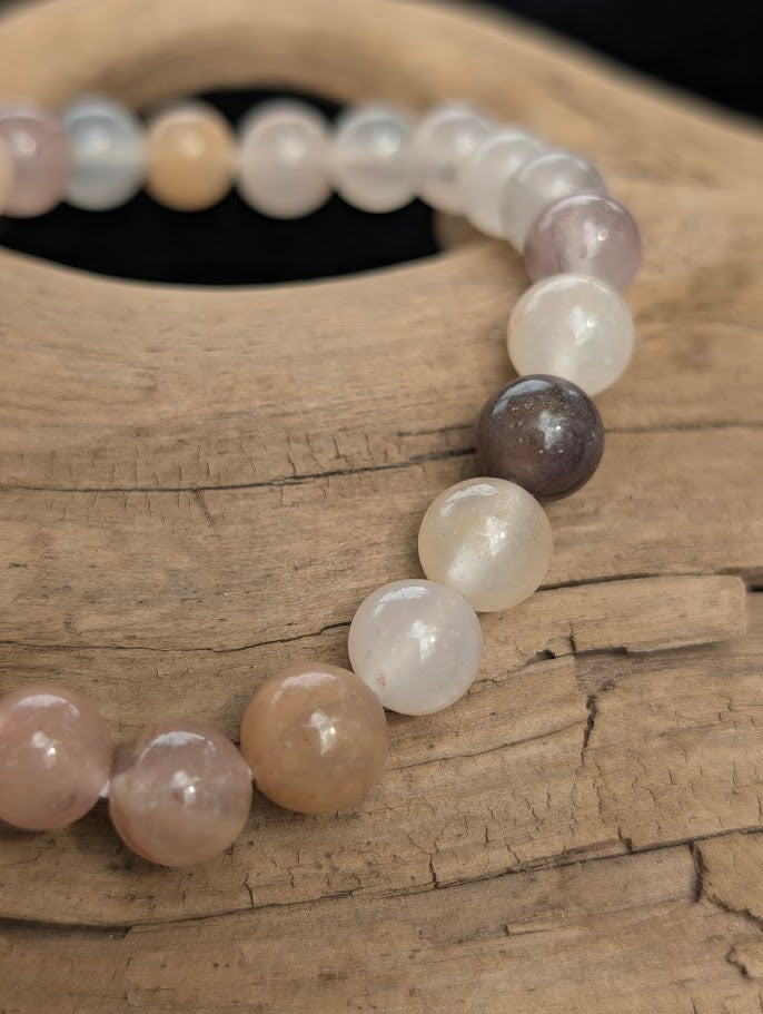 Macro view of polished 8mm Purple Aventurine spherical beads on driftwood, highlighting the natural translucency and muted, earthy plum hues.