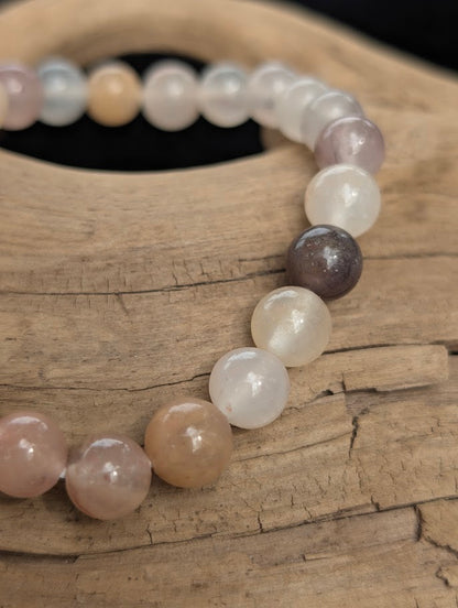 Macro view of polished 8mm Purple Aventurine spherical beads on driftwood, highlighting the natural translucency and muted, earthy plum hues.