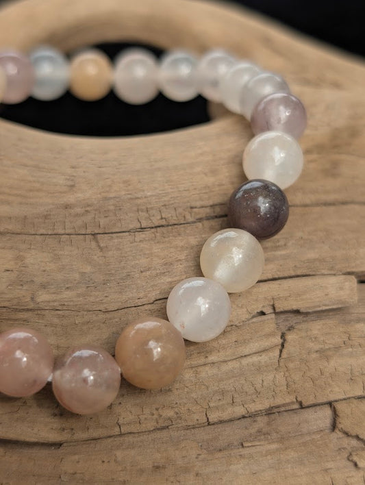 Macro view of polished 8mm Purple Aventurine spherical beads on driftwood, highlighting the natural translucency and muted, earthy plum hues.