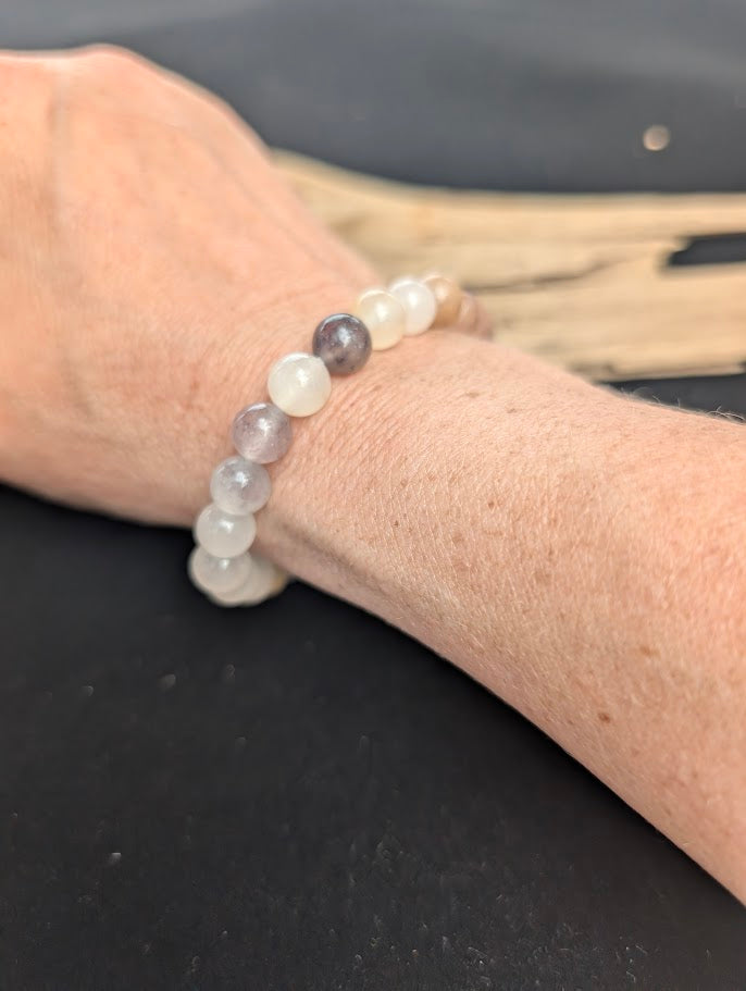 Natural sunlight on an 8mm muted purple and peach Purple Aventurine stretch bracelet worn on a wrist.