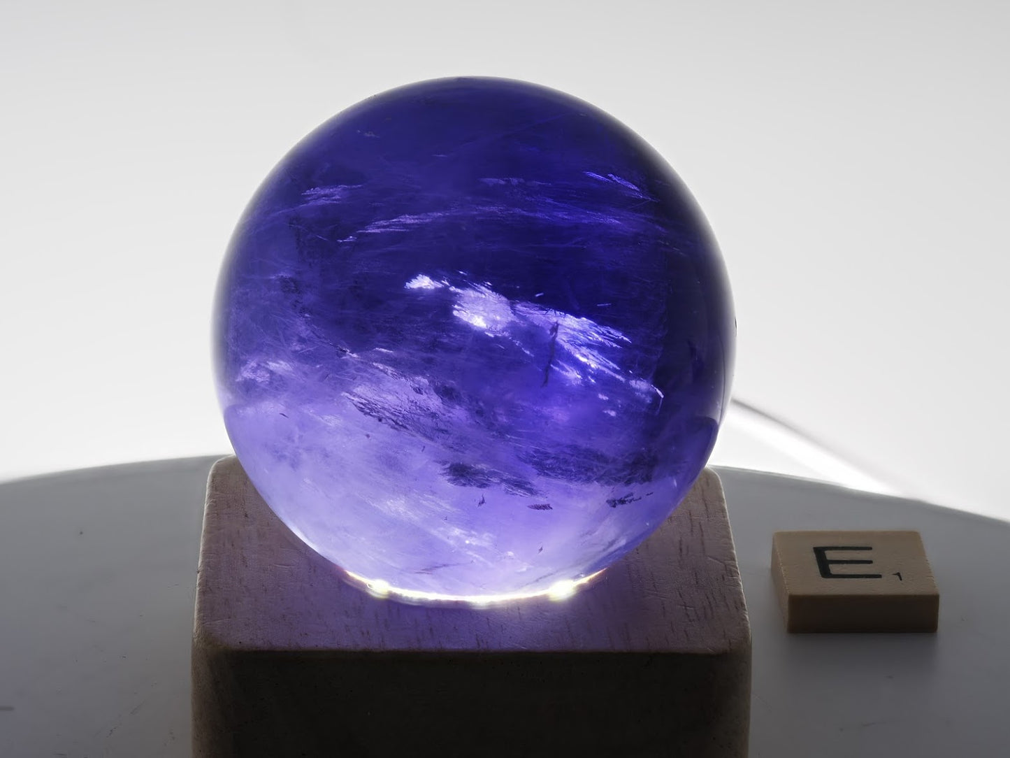 Backlit 57mm Purple Fluorite sphere specimen E revealing deep cathedral-like internal veils.