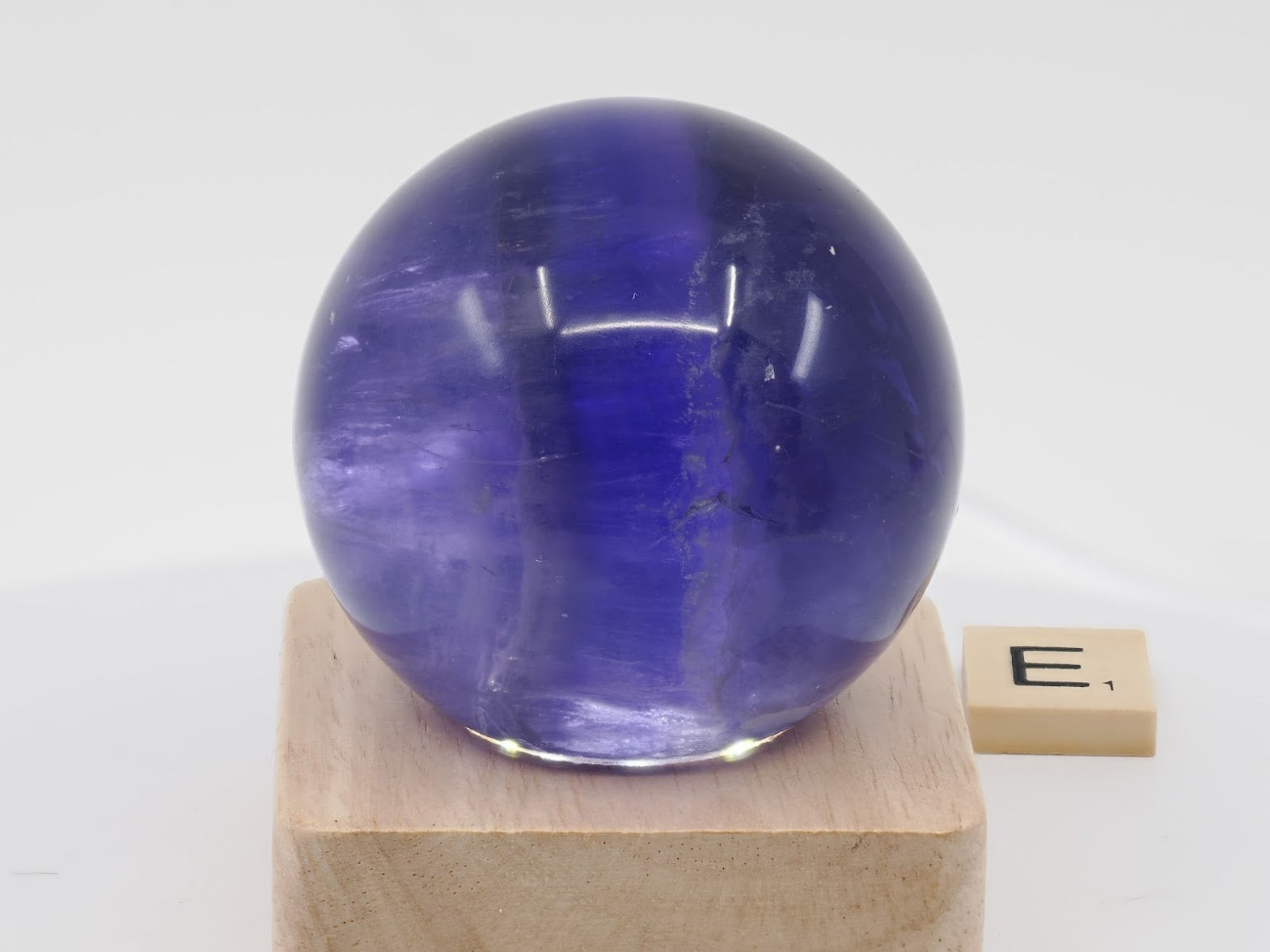 Detailed view of internal crystal structures within a polished 57mm Purple Fluorite sphere.