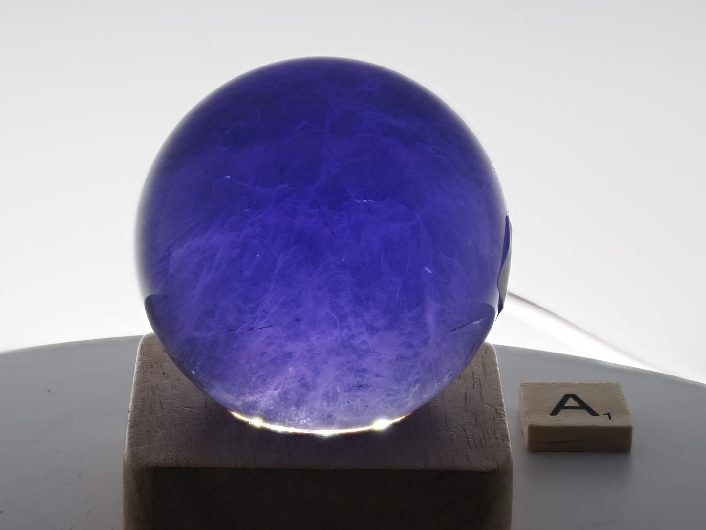 Backlit 59mm Purple Fluorite sphere specimen A showcasing rhythmic color banding and phantoms.