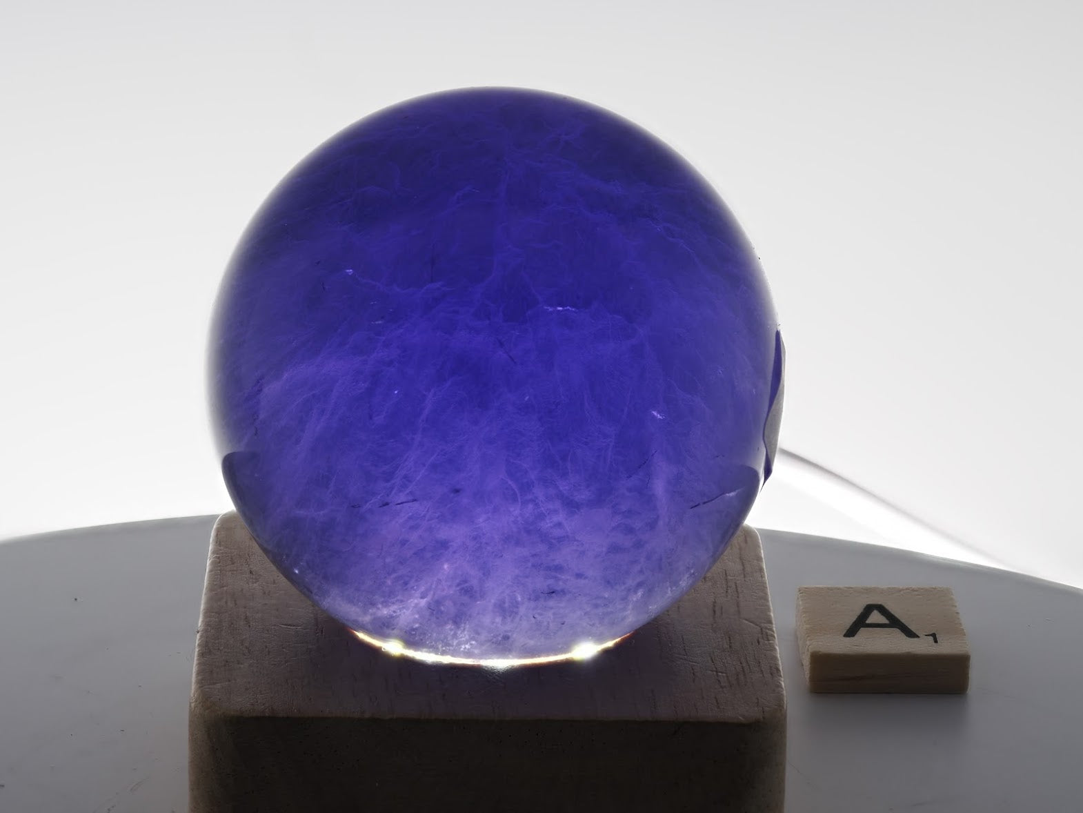 Backlit 59mm Purple Fluorite sphere specimen A showcasing rhythmic color banding and phantoms.