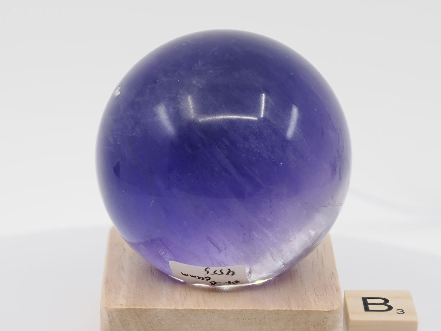 Backlit view of 64mm Purple Fluorite sphere revealing high-grade royal violet color saturation.