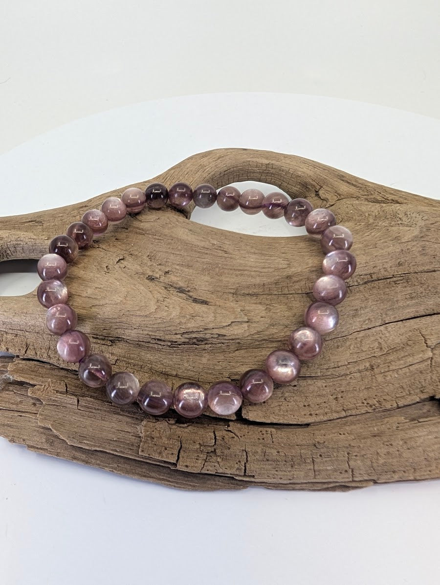 7mm Purple Mica Lepidolite bead bracelet from Brazil shown on a natural wood display showing deep purple color.