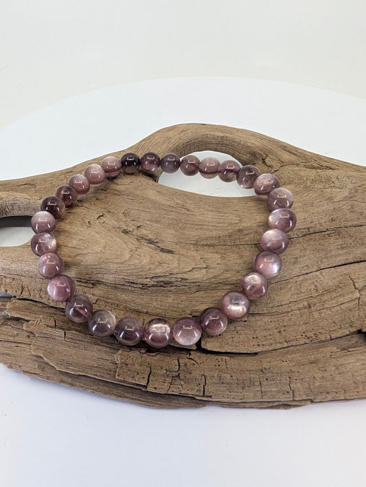 7mm Purple Mica Lepidolite bead bracelet from Brazil shown on a natural wood display showing deep purple color.