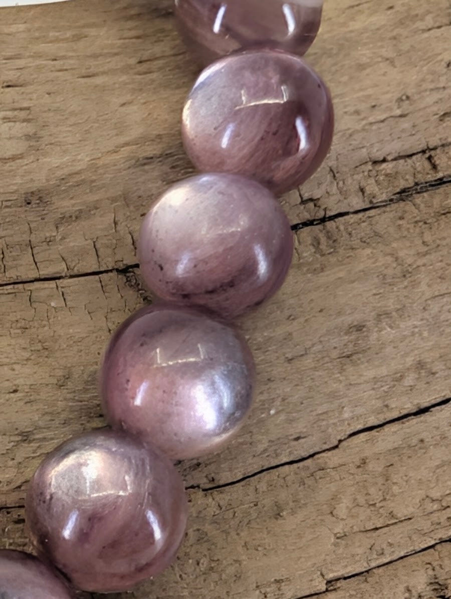 Macro view of Brazilian Purple Mica beads showing high-gloss polish and internal crystalline layers.
