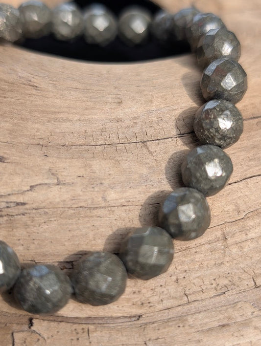 Macro close-up of 8mm faceted Pyrite beads highlighting geometric surface cuts and a highly reflective metallic finish.