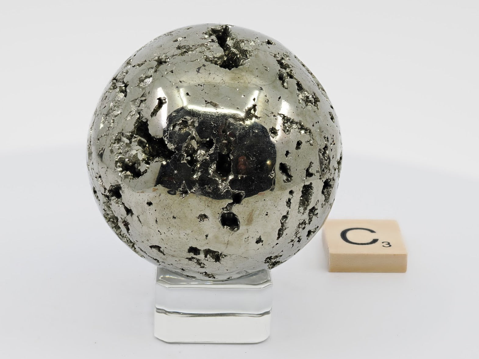 Polished Pyrite Sphere C displaying metallic mirror finish and natural vug texture.