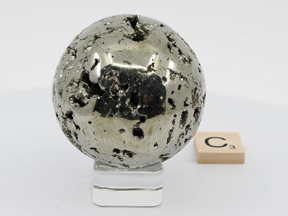 Polished Pyrite Sphere C displaying metallic mirror finish and natural vug texture.
