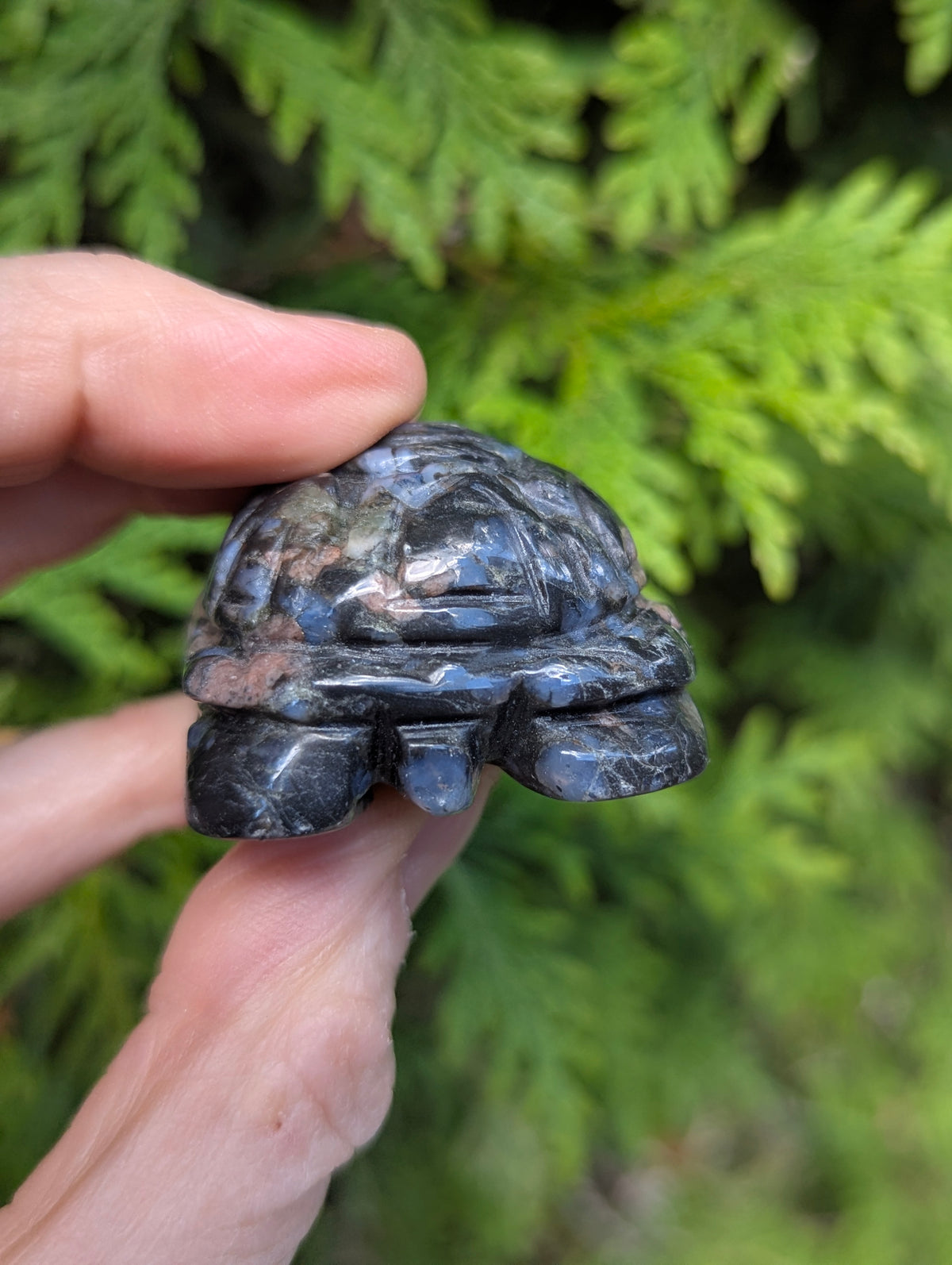 Rear angle of a hand-carved Que Sera Llanite turtle, showing the polished natural stone texture and stylized geometric shape.