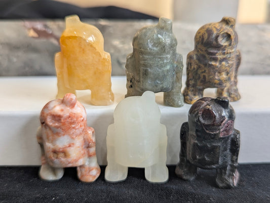 A group of six precision-carved R2-D2 totems in various natural minerals.