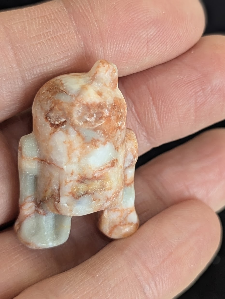 Front view of a 3cm R2-D2 carved from natural, mottled pink and white Jasper.