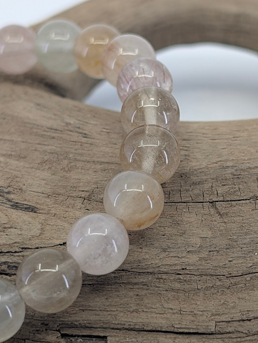 Close-up of 'Angora' 6.5mm Rabbit Hair Rutile beads showing the fine, golden TiO₂ inclusions and high quartz clarity.