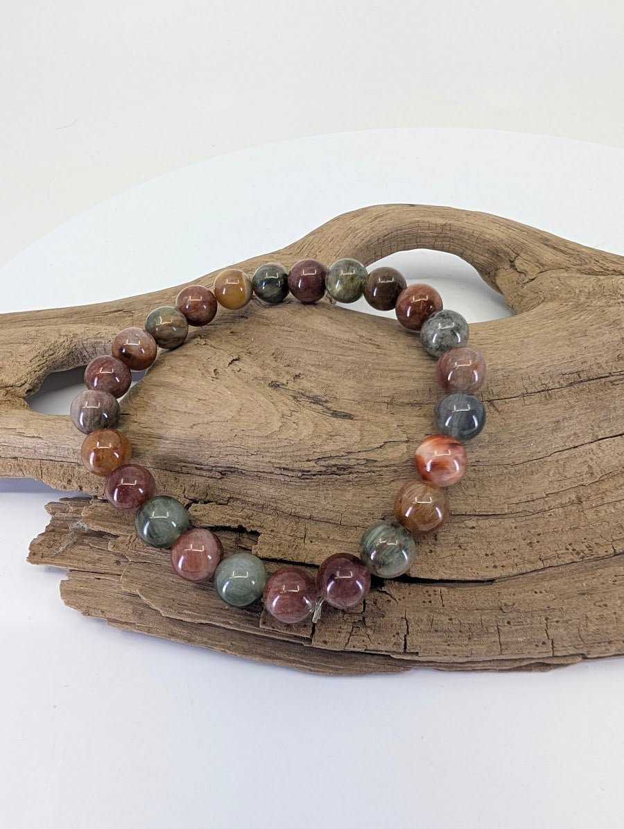 6.5mm Rabbit Hair Rutile Quartz bracelet in 'Earthy Multi' tones shown in a group setting on a wooden surface.