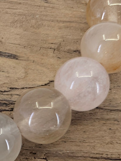 6.5mm Rabbit Hair Rutile Quartz bracelet in 'Angora' light tones displayed in a group with other mineral beads.