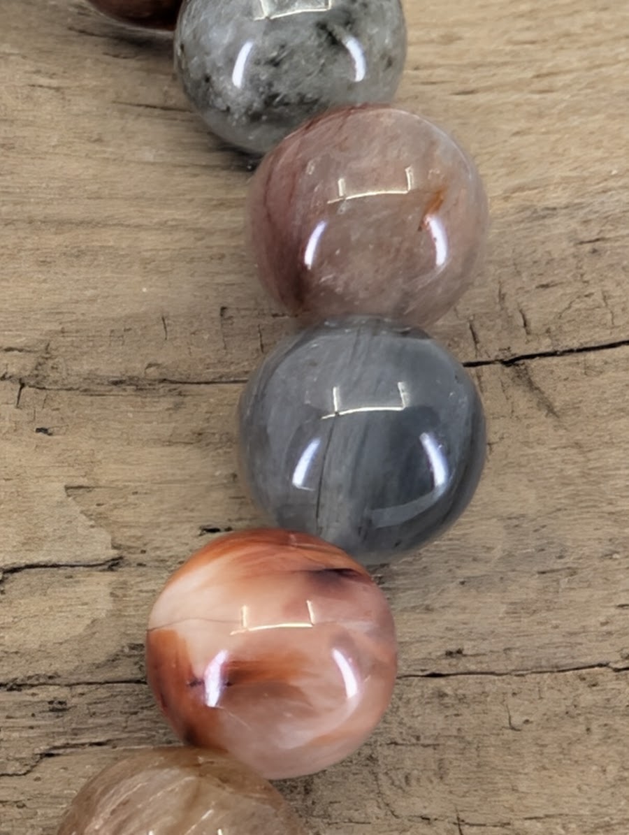 Macro view of 6.5mm Rabbit Hair Rutile Quartz beads highlighting the silky, fibrous sagenitic texture within the clear quartz.