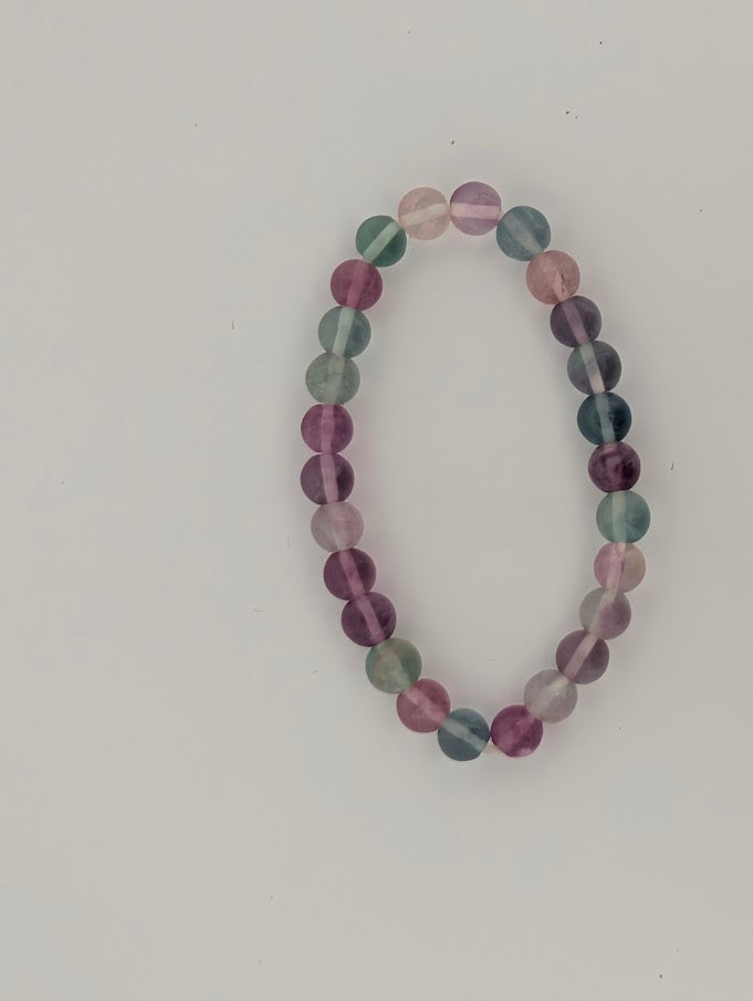 Top-down view of 6mm rainbow fluorite bracelet on white background