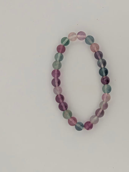 Top-down view of 6mm rainbow fluorite bracelet on white background