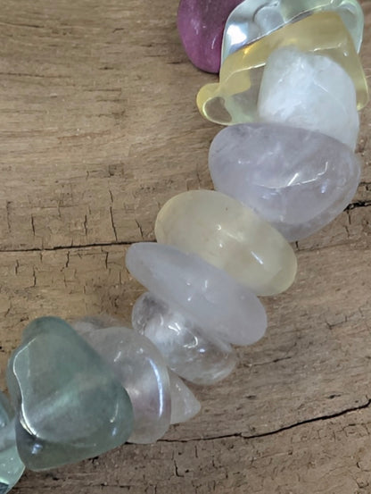 Macro shot of tumbled Rainbow Fluorite crystal chips, emphasizing the smooth edges and the clear, vibrant transparency of each unique shard.