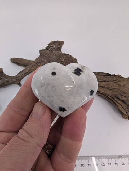 Hand holding a small 70g Rainbow Moonstone heart, ideal for pocket carry.