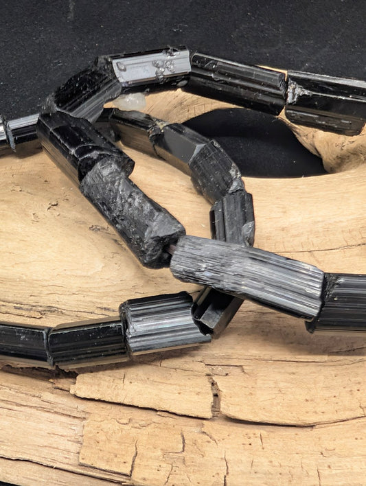Close-up comparing the Medium and Large raw Black Tourmaline crystal bars on elastic bracelets.