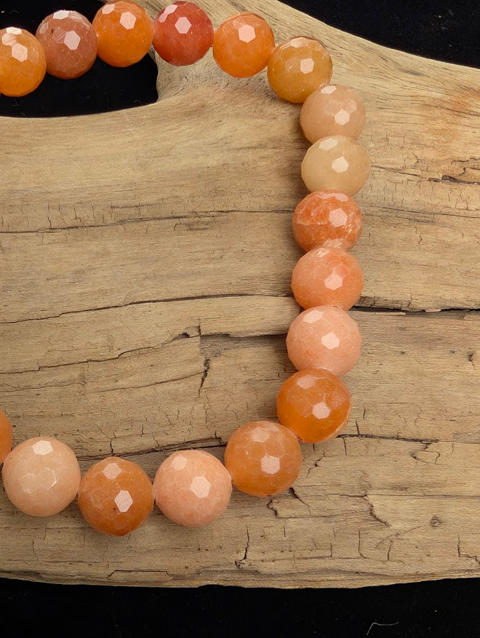 Macro close-up of 8mm faceted Red Aventurine beads highlighting the sharp lapidary cuts and natural shimmering aventurescence.