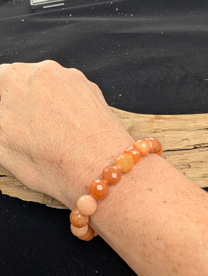 8mm faceted Red Aventurine stretch bracelet worn on a wrist for delicate size scale.