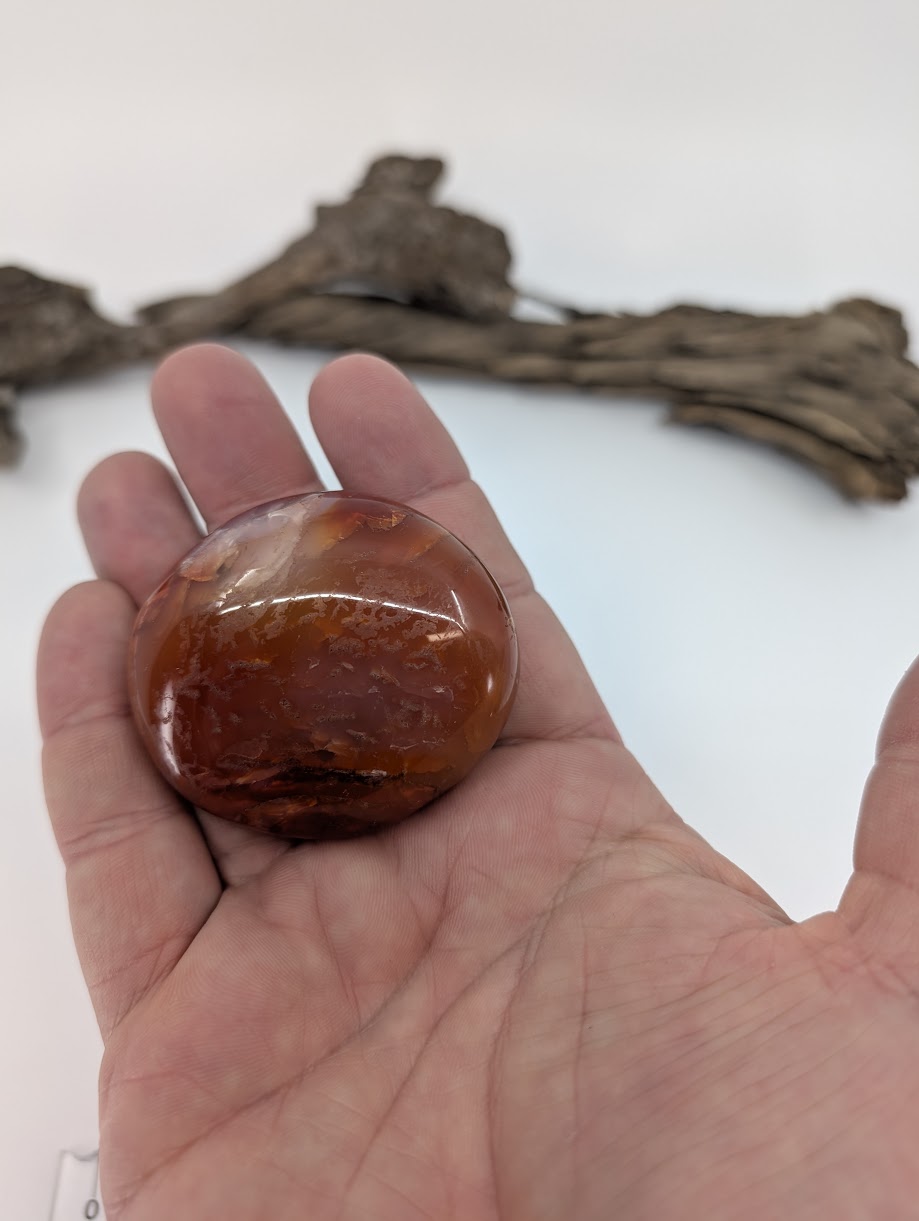 Red carnelian palm stone shown in hand highlighting polish and color depth