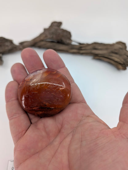 Red carnelian palm stone shown in hand highlighting polish and color depth