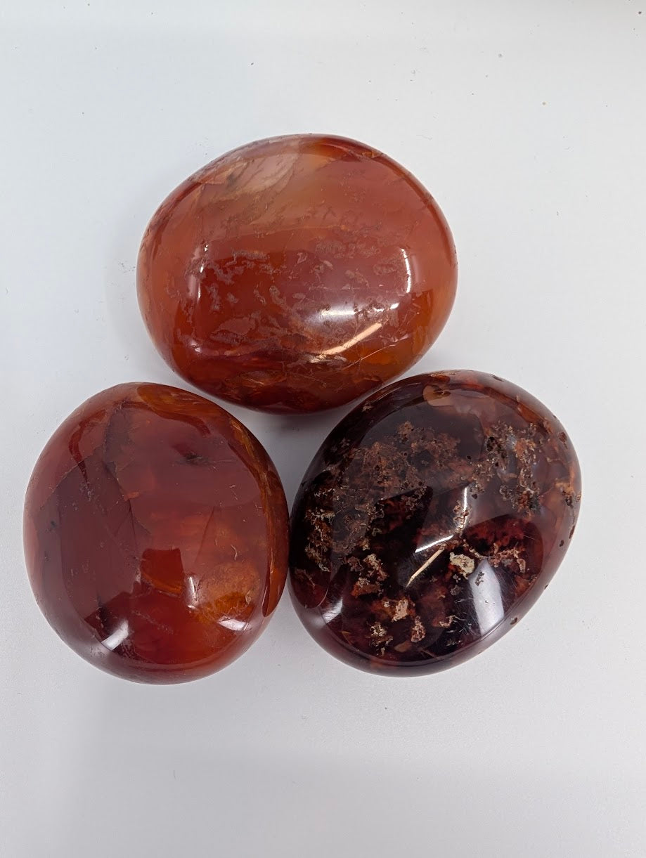 Close-up of polished red carnelian palm stones with natural translucency